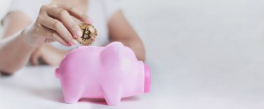 Altın bitcoin için pembe domuzcuk koyarak kadın shot eller yukarı kapatın 