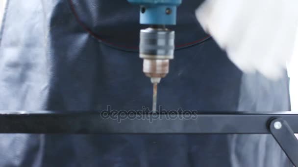 Gros plan mains de technicien à l'aide d'une perceuse électrique pour percer l'acier inoxydable noir avec un son ambiant faible profondeur de champ  