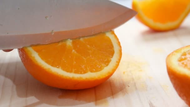 Cerca de tiro manos de la mujer usando cuchillo de cocina para cortar corte de naranja fresca y madura en madera tabla de cortar profundidad superficial de campo — Vídeos de Stock