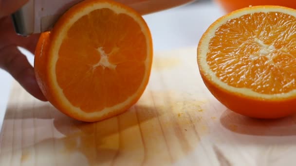 Close up shot hands of woman using kitchen knife to slash cut fresh and ripe orange on wood cutting board shallow depth of field — Stock Video
