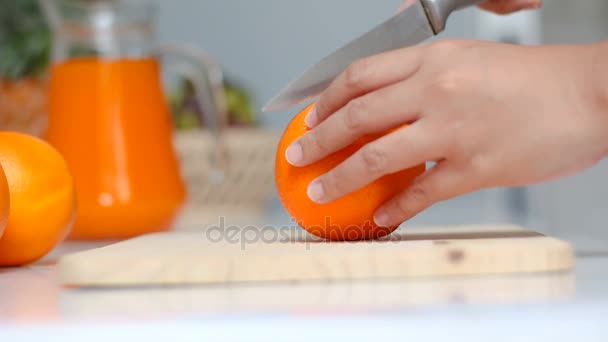 Close up shot hands of woman using kitchen knife to slash cut fresh and ripe orange on wood cutting board shallow depth of field — Stock Video