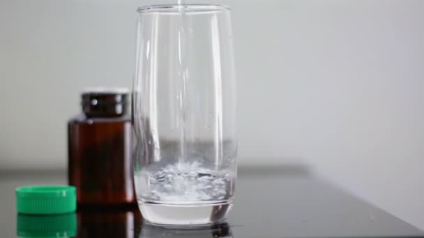 Close-up schot het water gieten in duidelijk glas voor eten de drug — Stockvideo