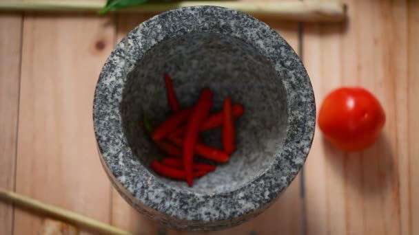 Bovenaanzicht handen van vrouw zetten rode warme verse Spaanse peper en knoflook in mortel steen bereiden mengen kruid kruiden voor het koken van Thais eten warme Toon verwerkt — Stockvideo