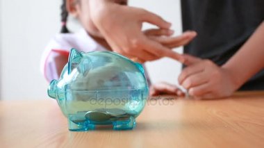 Asyalı küçük kız Tay anaokulu öğrencisi üniformalı para sikke açık kumbara koyarak seçin ortam ses ile eğitim kavramı için para tasarrufu domuz odaklanmak