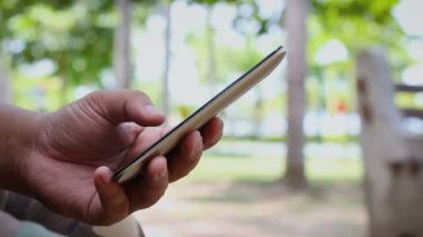 Ortam ses ile bir doğa Park mobil akıllı telefon kullanan adam shot el kadar kapatın 