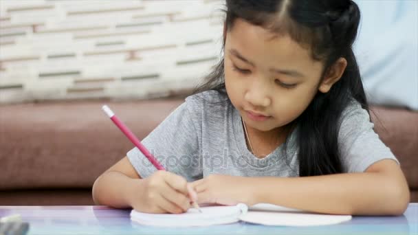 Close-up shot Aziatische meisje met potlood schrijven een notitie boek huiswerk met concentratie voor thuis, school en onderwijs concept — Stockvideo