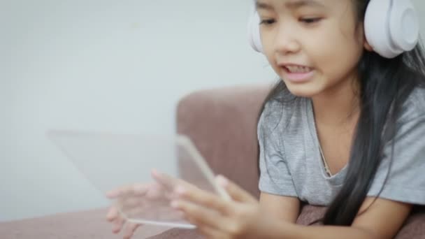 Menina asiática usando fone de ouvido sem fio branco e almofada clara para conceito de aplicação móvel de tecnologia futurista — Vídeo de Stock