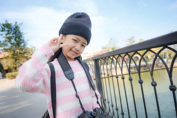 Азиатская маленькая девочка улыбается и показывает знак победы со счастьем — стоковое фото