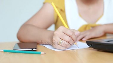 Dizüstü bilgisayar ve kullanım Kalem kağıda yazı yazarak kadın elinde el sığ derinlik-in tarla ortam ses ile odak seçin