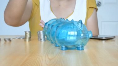 Kadının elleri parayı boş metaforla 4 açık domuz kumbarasına koyuyor. Harcamak ve tasarruf etmek için ayırdığı para farklı bütçe finansal konsepti.