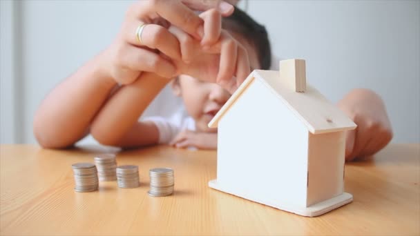 母亲和亚洲小女孩把钱硬币房子存钱罐选择集中在房子上 — 图库视频影像