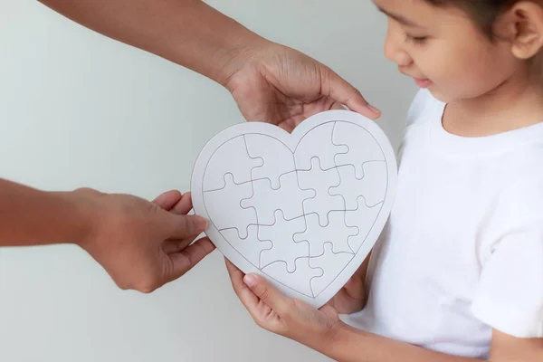 Asiatisches kleines Mädchen nimmt Puzzle von ihrer Mutter für Familie — Stockfoto