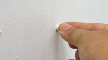 Bir adam çekim el yakından eklemek Çimento Beton beyaz duvar ve onu vurmak için çekiç kullanarak tutmak için içinde plastik Koç boynuzu