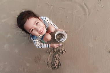 Top view portriat Asian little girl playing on the sand beach wi clipart