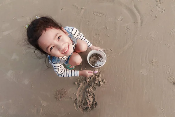Маленькая азиатская девочка, играющая на песчаном пляже — стоковое фото