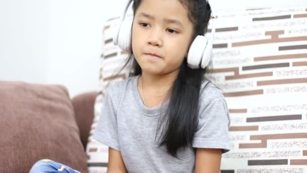 アジアの少女は白い無線ヘッドフォン技術モバイル アプリケーション概念で音楽を聴く — ストック動画