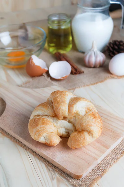 Croissant na placa de corte de madeira na madeira de mesa e tecido selecione fo — Fotografia de Stock