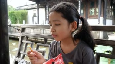 Şirin Asyalı küçük kız mutluluk ile snack yeme