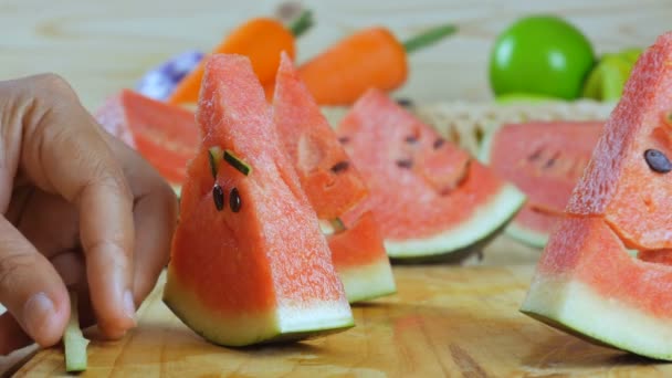 夏のカット板の新鮮なフルーツの熟したスイカの切り身をクローズ アップ ショットの手が顔を笑わせること — ストック動画