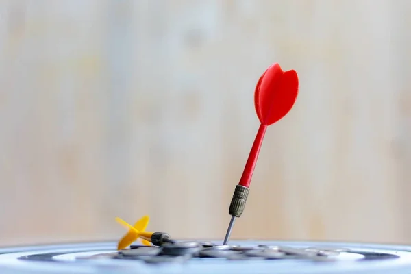 Red dart arrow hit the center target of dartboard and money coin — Stock Photo, Image