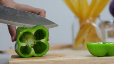 Kadının elleri mutfak bıçağı dilimi ve çan biberini keserek yemek pişirmeye hazırlanıyor.