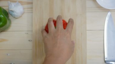 Kadının elleri mutfak bıçağı dilimi ve çan biberini keserek yemek pişirmeye hazırlanıyor.