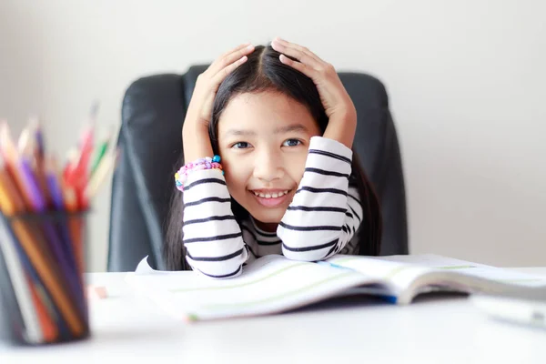 Feliz niña asiática haciendo la tarea y sonriendo para auto lear —  Fotos de Stock
