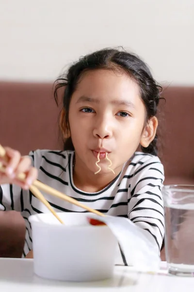 Feliz pouco ásia menina sentado no branco mesa para comer instantâneo — Fotografia de Stock