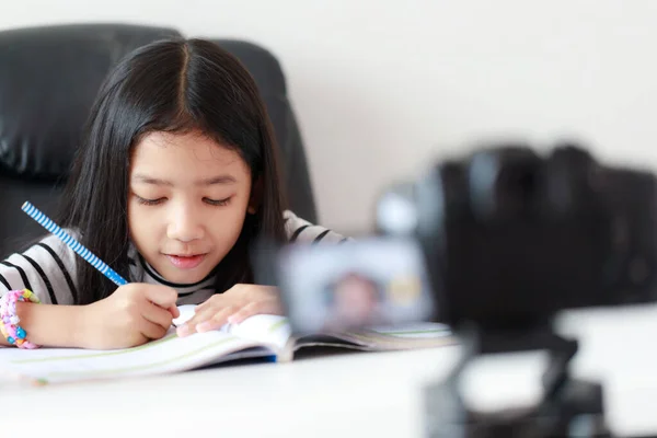 Маленька азіатська дівчинка сидить за білим столом і живе потоком. — стокове фото