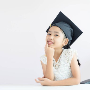 Portre küçük Asyalı kız lisansüstü şapka ve gülümseme zekâ giyiyor