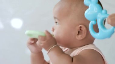 Küçük şirin Asyalı bebek oturuyor ve mutlulukla oynuyor.