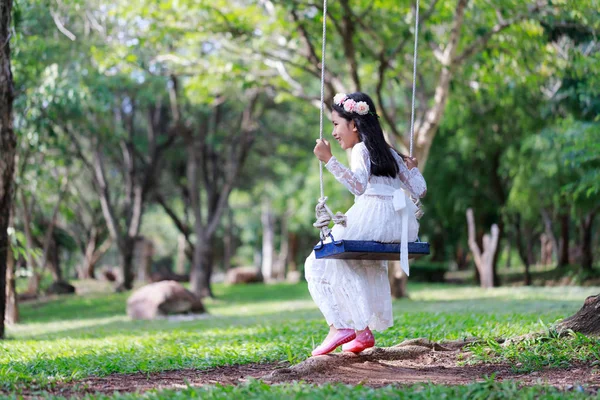 Retrato de pouco ásia menina jogar o balanço sob o Grande tr — Fotografia de Stock