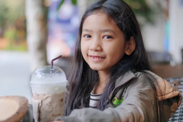 Portrait shot of the little Asian girl drinking chocolate milk a — Stock Photo, Image