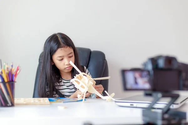 Маленькая азиатская девочка ползает по деревянной модели и ведет прямую трансляцию — стоковое фото