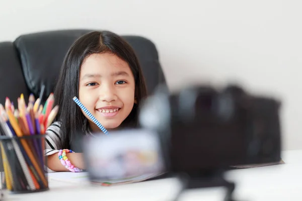 Pequeña chica asiática sentada en la mesa blanca y transmisión en vivo —  Fotos de Stock