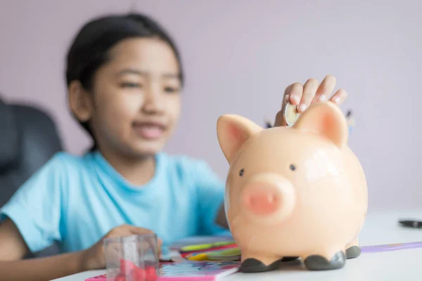 Feliz poco asiático chica poner dinero moneda en piggy banco selec — Foto de Stock