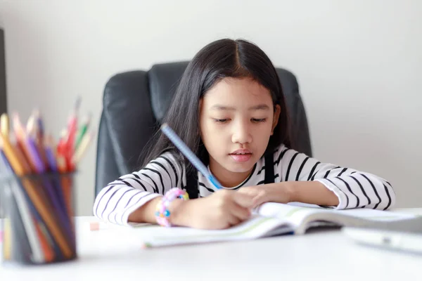 Pequeña chica asiática haciendo tarea para el autoaprendizaje y la educación —  Fotos de Stock