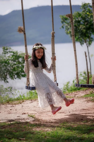 Portrait of little Asian girl playing the swing in the nature pu — Stok fotoğraf