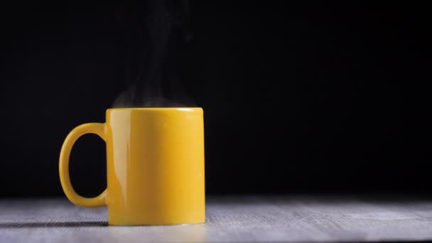 黄色のマグカップは黒の背景に煙と熱いコーヒーが含まれています — ストック動画