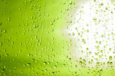 Mavi su damlaları. Yeşil arka planda bir damla su. Cama su damlaları