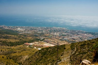 Dağlar, onların altındaki şehir ve sisin içindeki deniz.