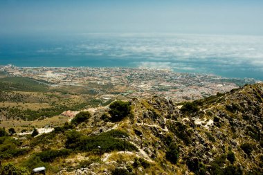 Dağlar, uzak bir şehir arkalarında ve deniz.