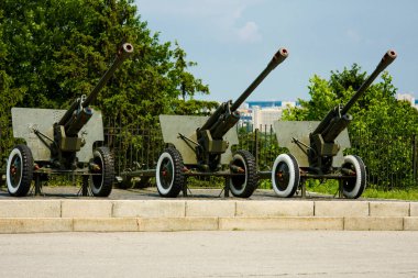 Üç eski top yeşil ağaçların arka planına karşı bir kaide üzerinde