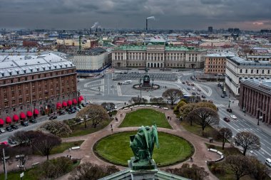 Kare, yeşil çimen, bina ve karanlık gökyüzü