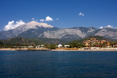 Deniz, sahil, oteller, yeşillik, dağlar ve gökyüzü