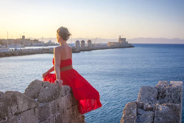 Dívka Červených Šatech Sedí Kameni Obdivuje Moře — Stock fotografie