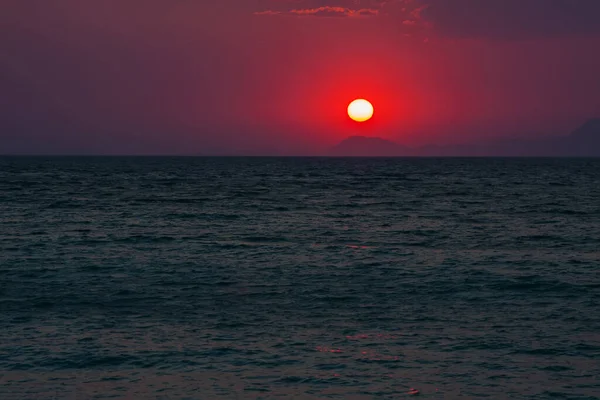 Kızıl Akşam Güneşi Denizin Üzerindeki Uzak Bir Dağın Üzerinde Batıyor — Stok fotoğraf