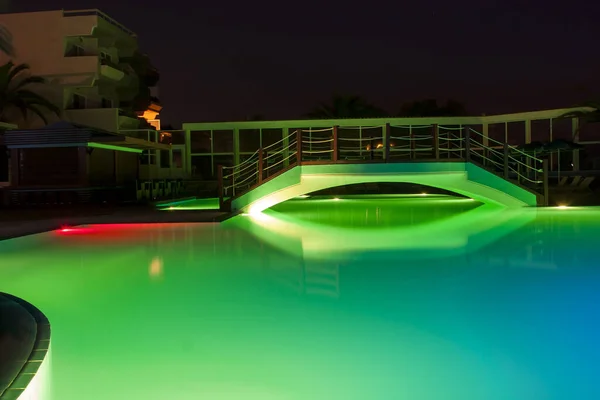 Hotel night swimming pool with a bridge and beautiful lighting