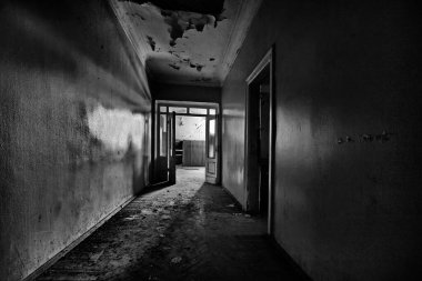 Terk edilmiş bir evin sonunda eski bir kapısı ve ışığı olan koridor.