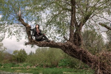 Nehirdeki suyun üstündeki ağaçta oturan kız.